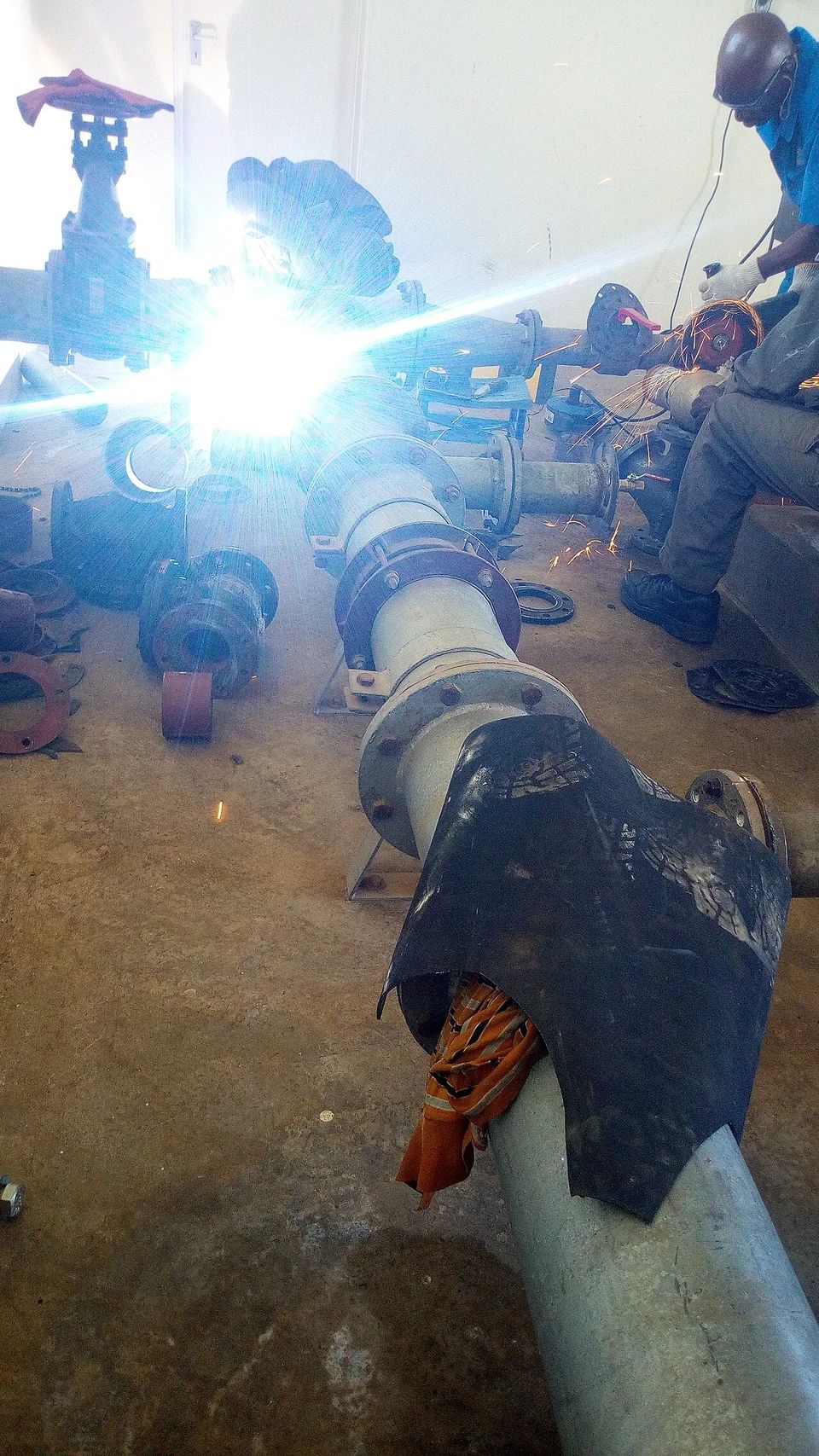 Workers welding pipework during installation of water pumps and motors