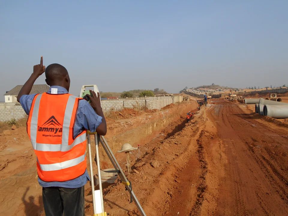 Surveyor using a total station at an active construction site