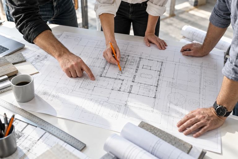 Illustrative overhead view of colleagues reviewing a construction drawing