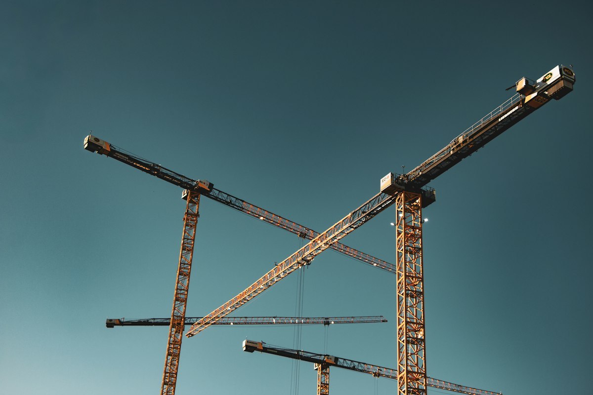 Tower cranes above construction works against a blue sky