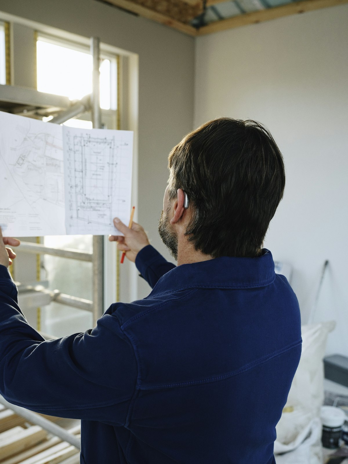 A construction professional reviewing building plans on site