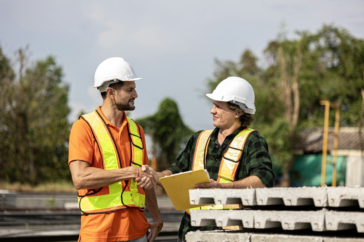 Two construction professionals shaking hands in a concrete production factory