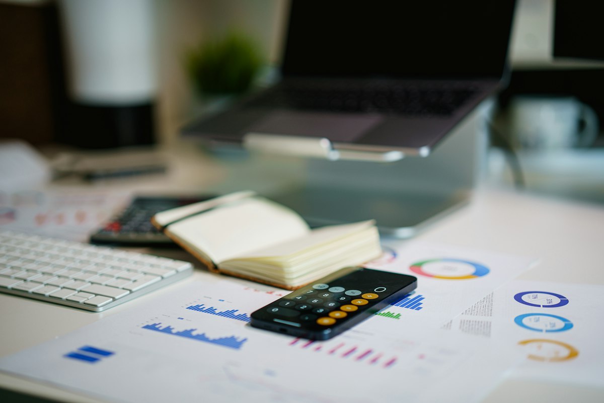 Financial reports, charts and a smartphone arranged on a work desk