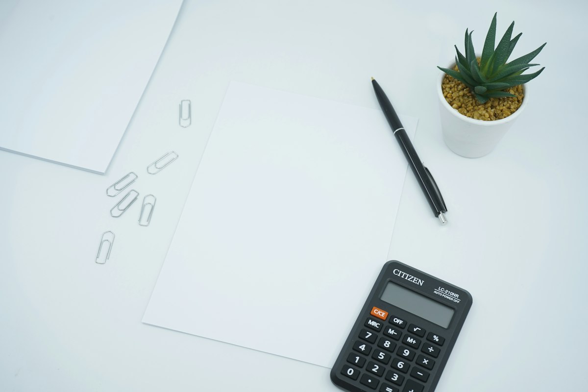 Calculator, pen and a sheet of paper on a work desk
