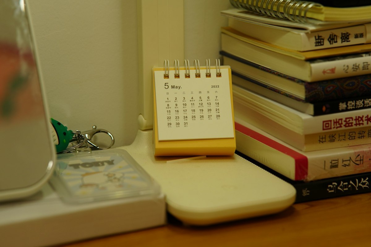Desk calendar beside books, representing the timing of planned expenditure