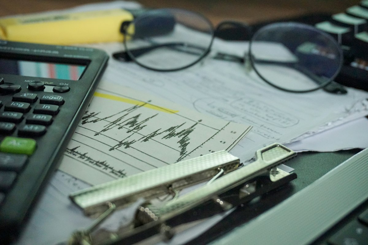 Finance work desk with a calculator, reports and eyeglasses