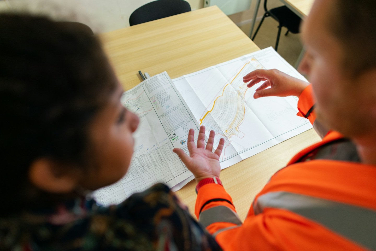 Civil engineers discussing a river and weir plan on a desk