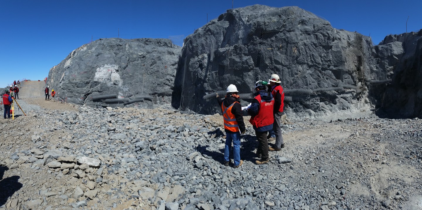 Construction professionals reviewing plans in the excavated rock foundation of the Rubin Observatory on Cerro Pachón, Chile