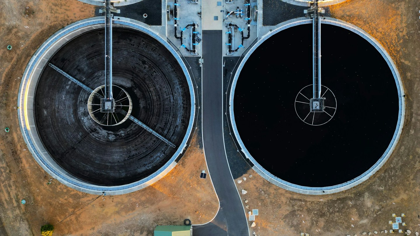 Top-down aerial view of two circular water-treatment tanks and their radial scraper bridges in Perth