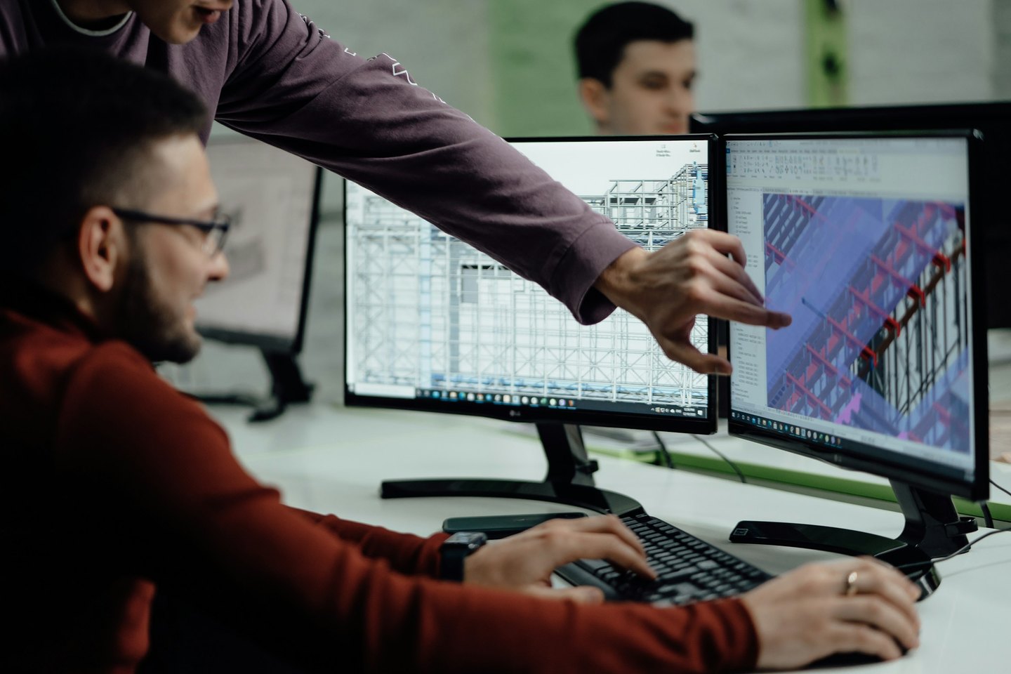 Colleagues review structural building models on two computer monitors.