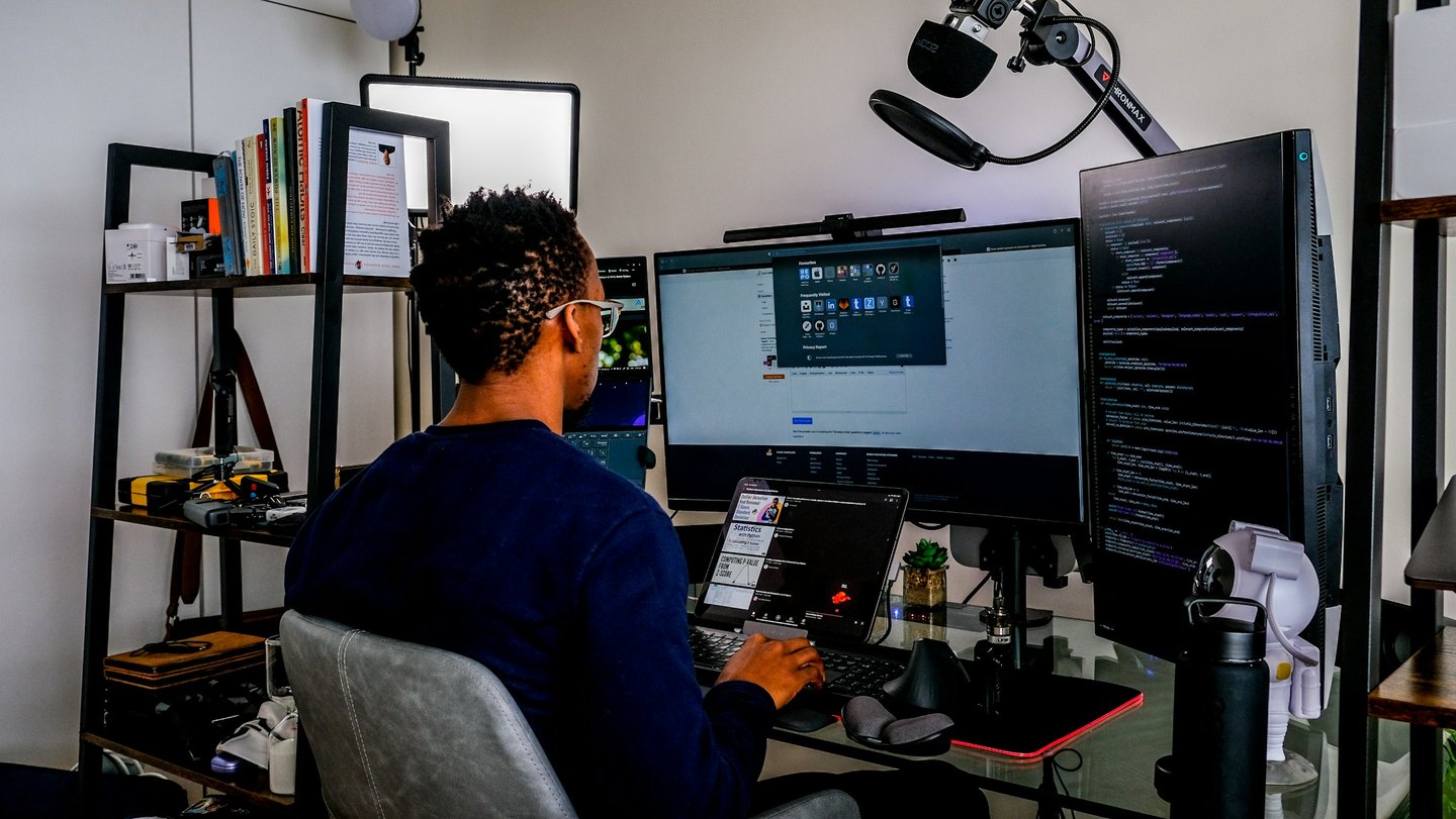 A person works at a desk with code displayed on a vertical monitor.