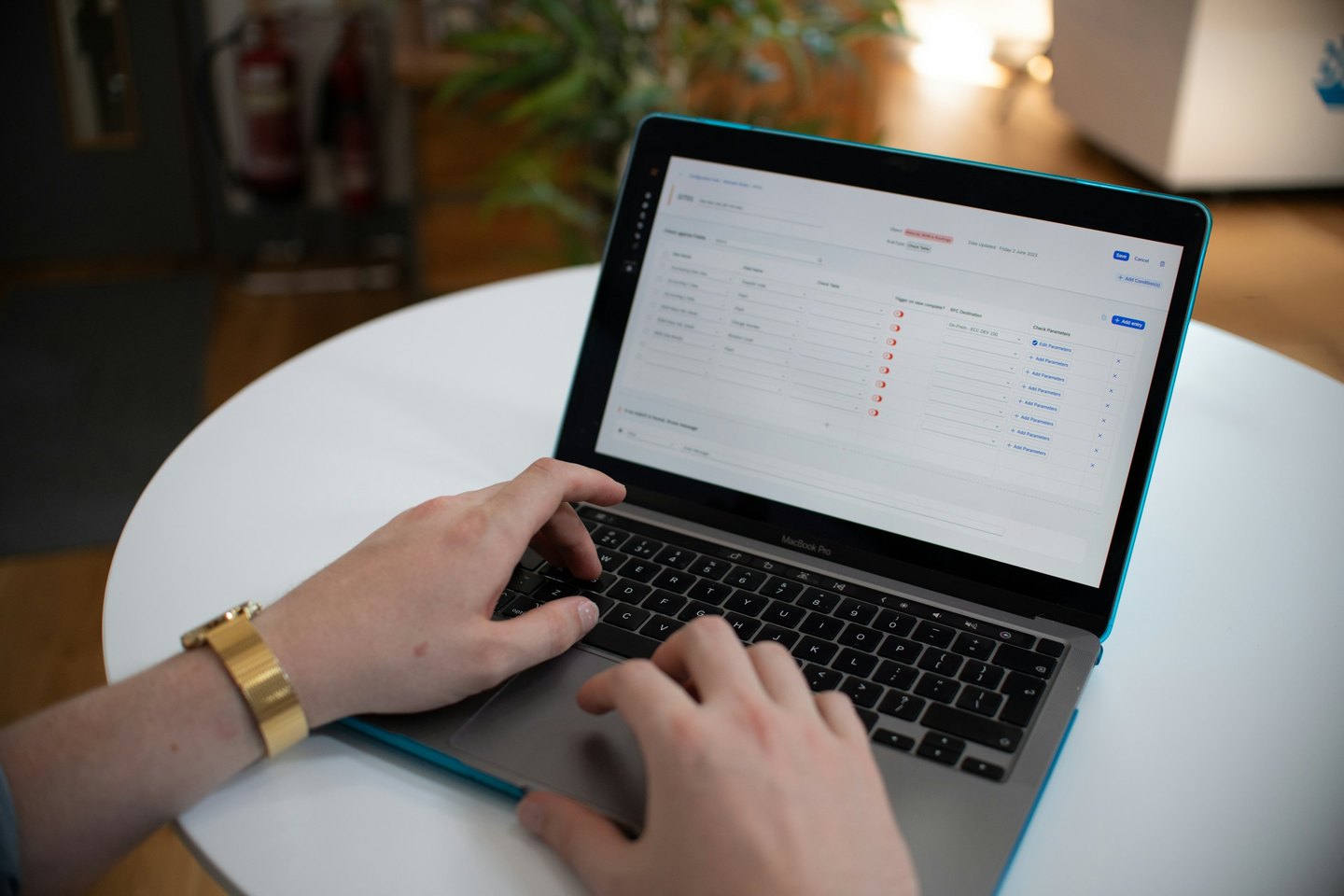 Hands using a laptop displaying a data management form.