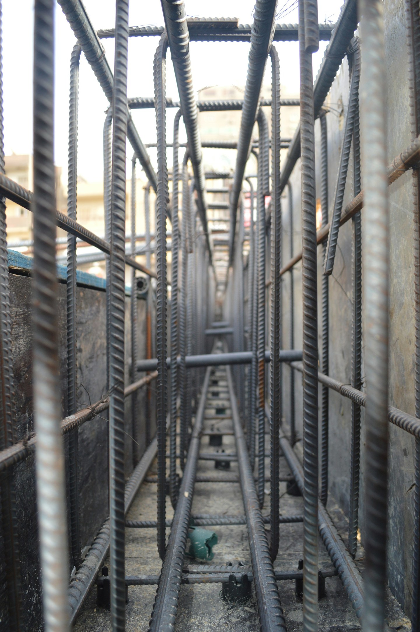A view along closely spaced steel reinforcement bars inside a narrow concrete beam form